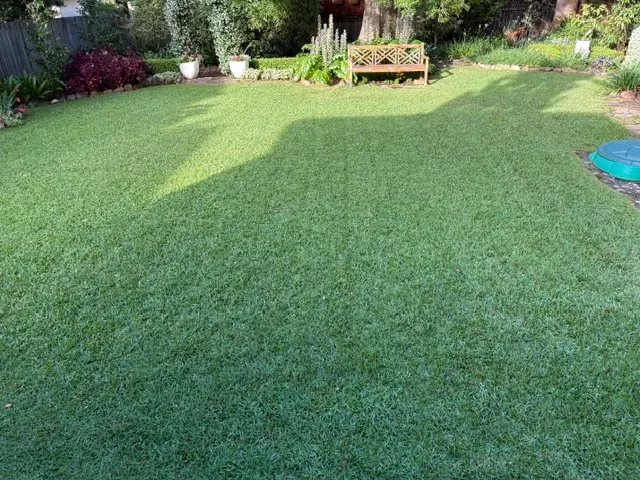 Neatly mowed back lawn with a garden bench and flower beds on the Upper North Shore